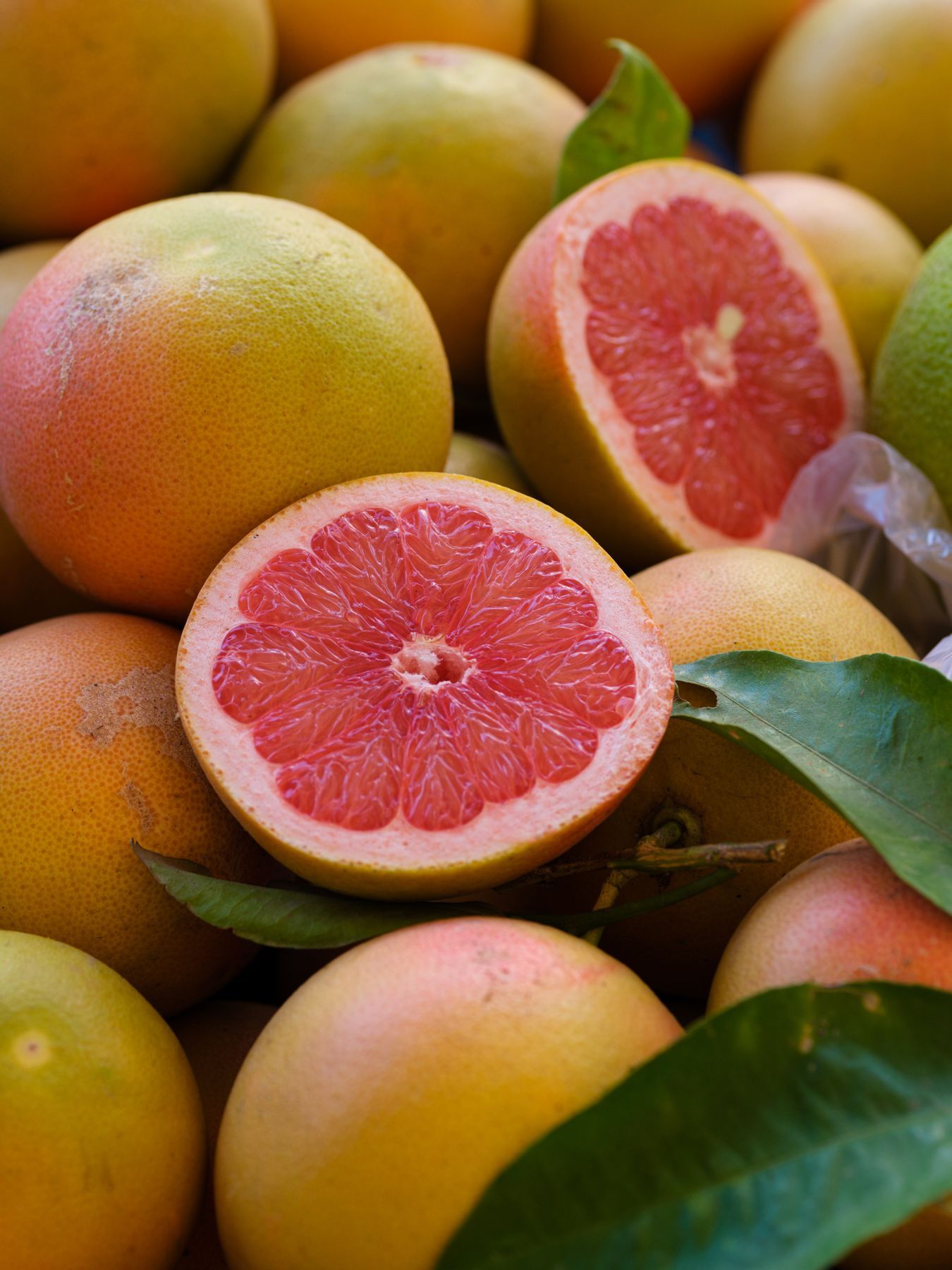Fresh pink grapefruit sliced in half on white surface